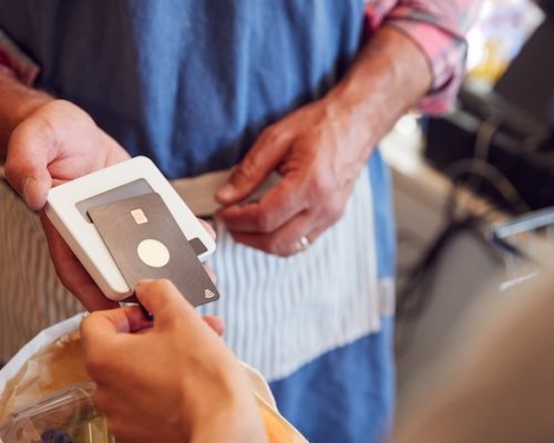 Close Up Of Customer At Checkout Of Organic Farm Shop Making Contactless Payment