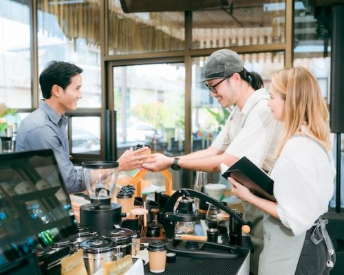 Smiling waitress wear apron take order talk to clients serving restaurant guests choosing food drinks menu in cafe coffeehouse bar, waiting staff, good customer service, cashier serving customers